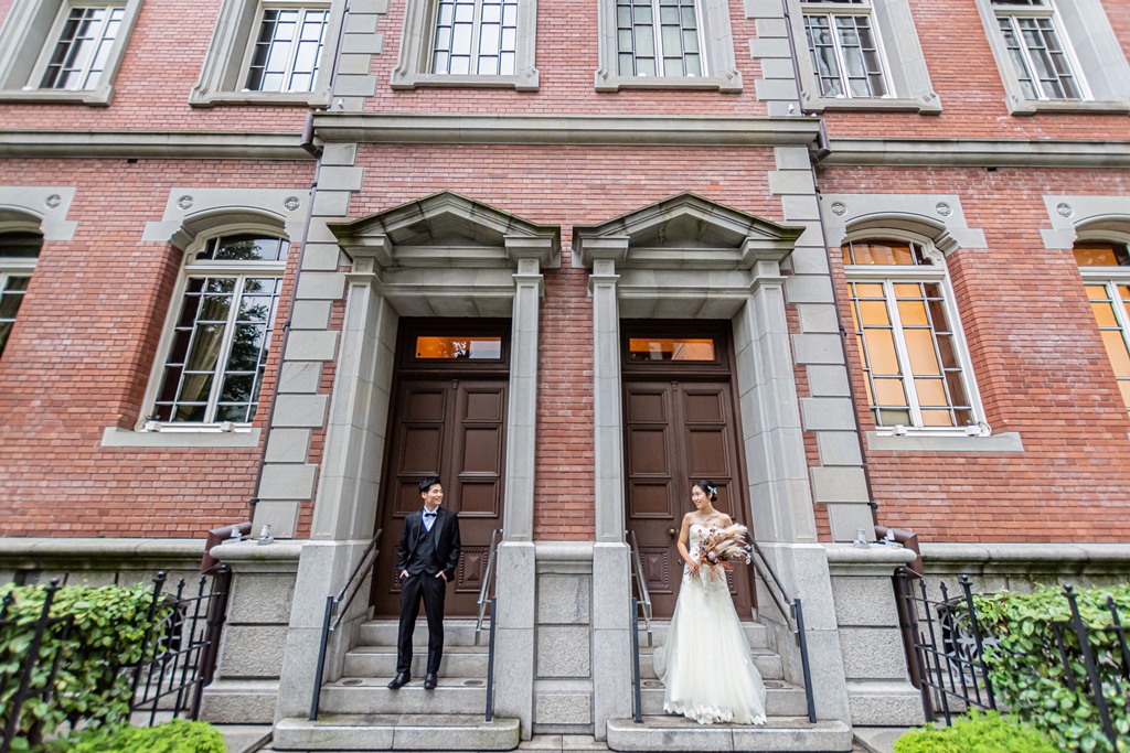 赤レンガ造りの三菱美術館、双子の扉の前の階段にそれぞれ立つ新郎新婦。