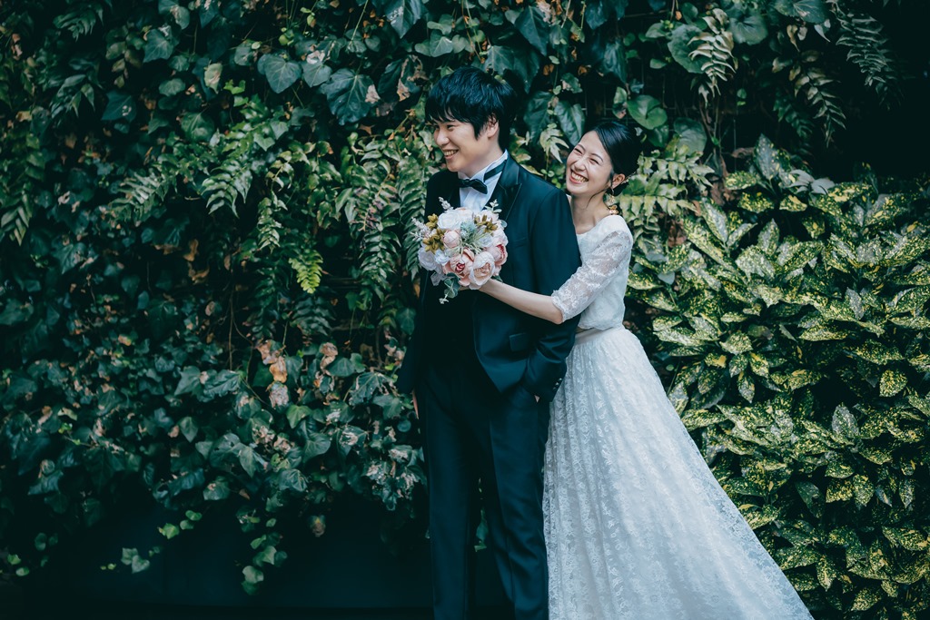 東京駅丸の内駅舎を背景に、ドライブーケを手に振り向き合う新郎新婦のロケーションフォト。