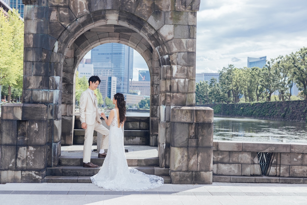 石造りアーチ門の下、和田倉濠を背景に手をつなぎ向き合う新郎新婦。