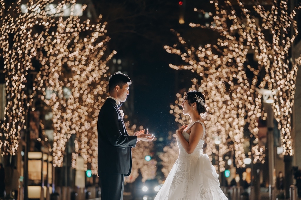 光のトンネルの中を歩く新郎新婦、ドレスの裾がふわりと揺れる。