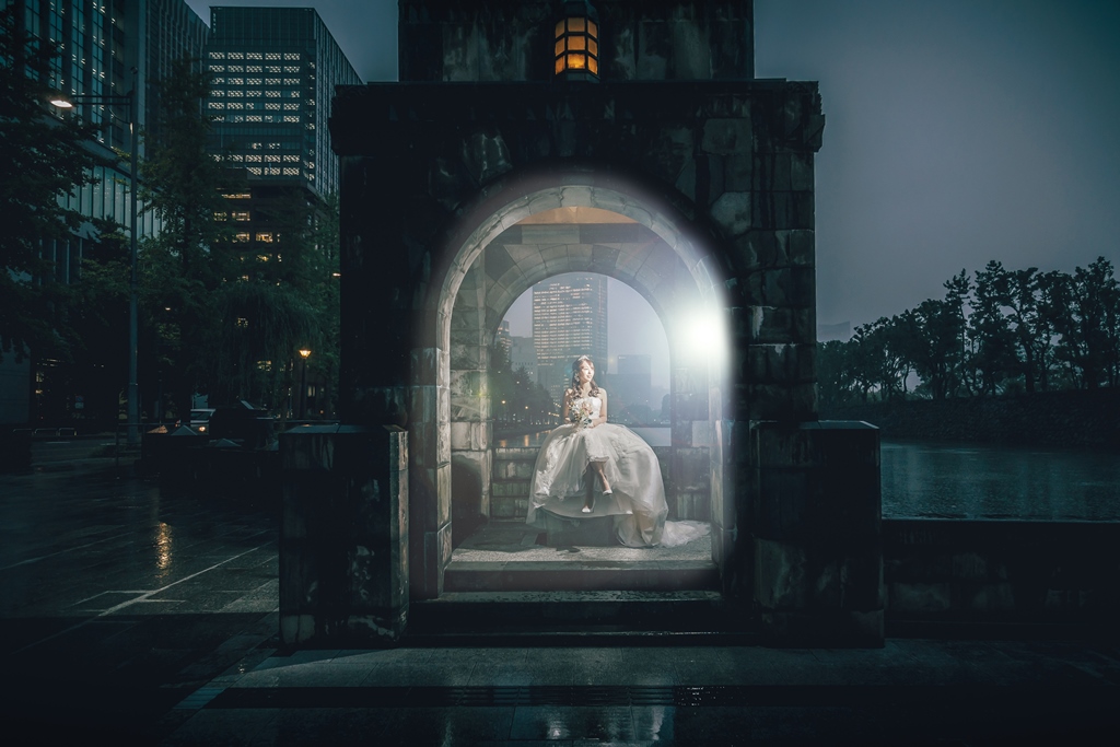石造りアーチの明かりに照らされ、堀端に座る新婦、ライトアップされた幻想的な雰囲気。