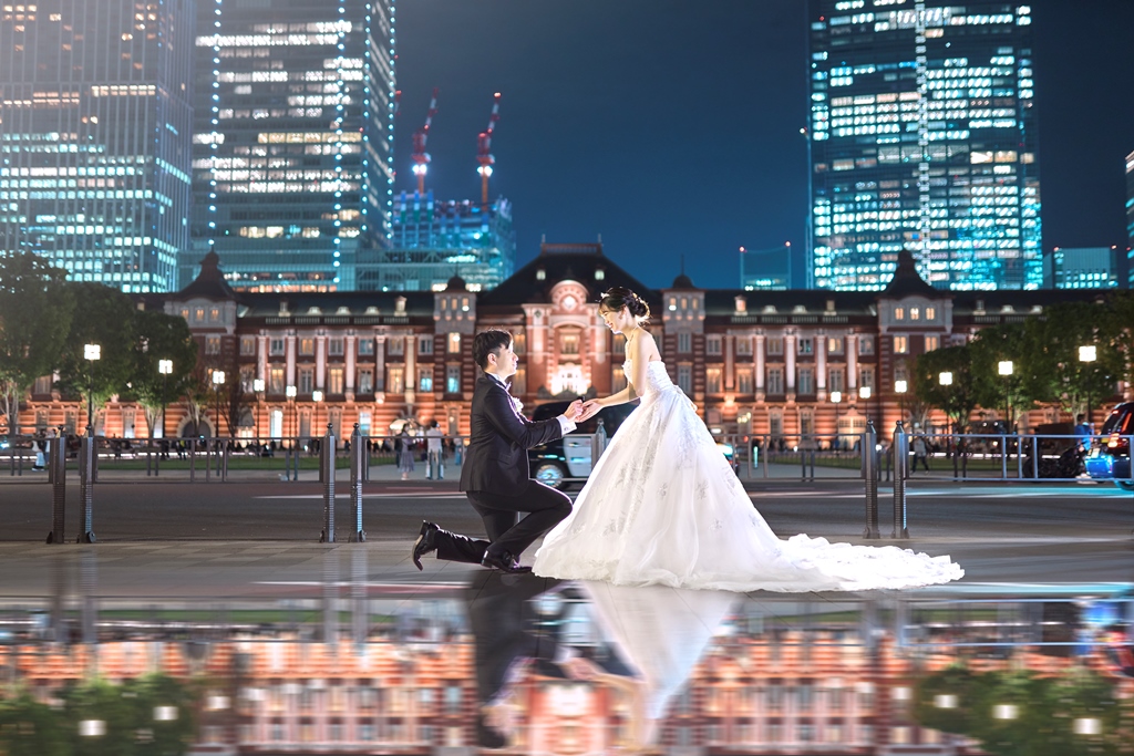 夜の東京駅前を歩く新郎新婦の足元のアップ、白いブーツと黒い革靴。