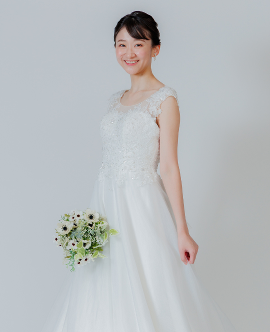Aライン（TL04）：ノースリーブのすっきりとしたシルエットには繊細なレースが施され、透明感のあるディテールが肌を美しく引き立てます。スカート部分には軽やかなチュールを贅沢に使用。バックにはリボンをあしらい、シンプルな中にも可憐なアクセントを添えています。