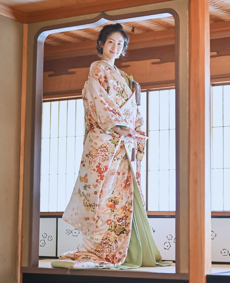 小春日向（OMOS07）：淡いサーモンピンクの上に、梅や藤が芽を開く豪華な色打掛。細かくデザインされた刺繍と、大人っぽさを兼ね備えた至高の一着です。