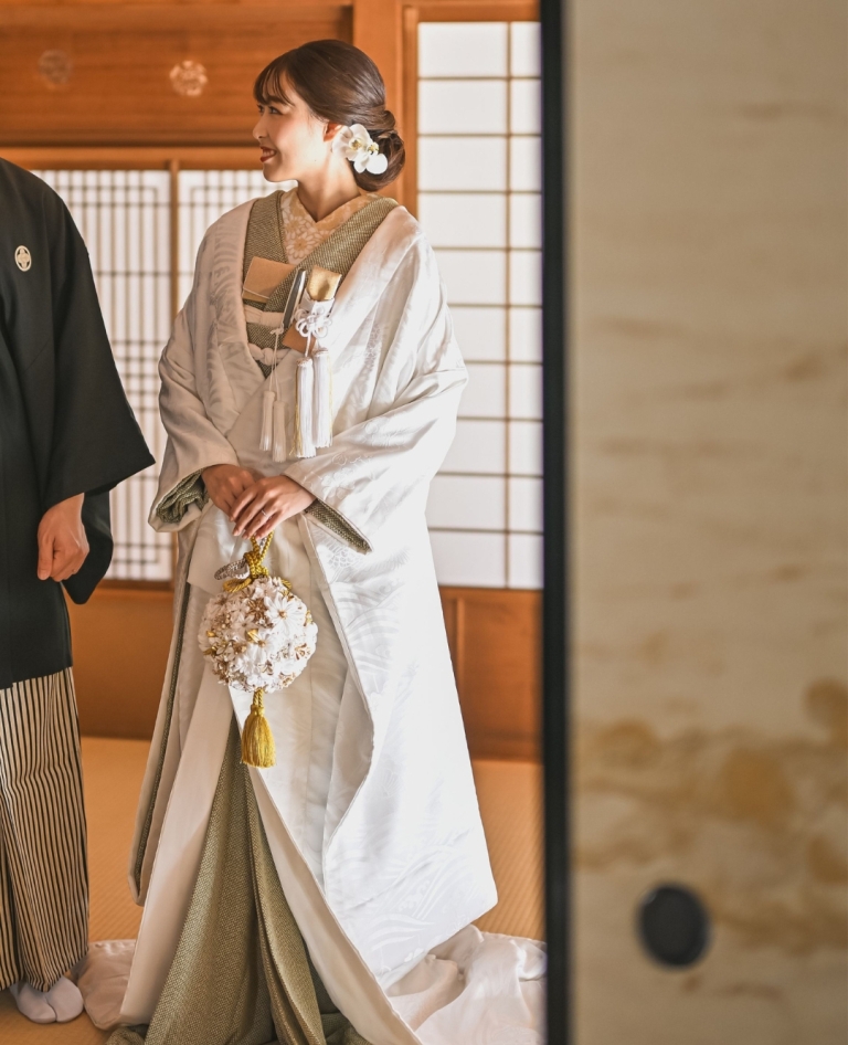 波模様が織り込まれたホワイトの白無垢は、静かに広がる水面のように上品で凛とした印象を与えます。絞りグリーンの色掛下はマリーゴールドの和装小物との相性もGood!