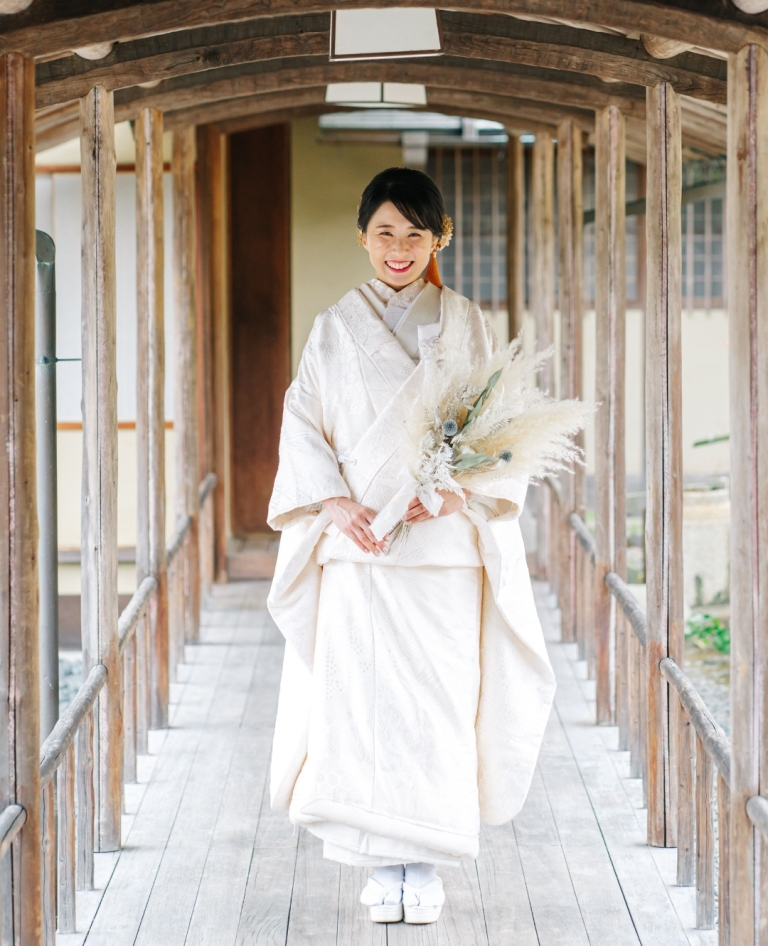 繊細な花柄が上品に織り込まれた白無垢。純白の中にほのかな華やぎが宿り、伝統美と可憐さをあわせ持つ一着。