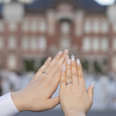 東京駅丸の内駅舎を背景に、手のひらを合わせる新郎新婦の結婚指輪。ディテールを捉えたウェディングフォト