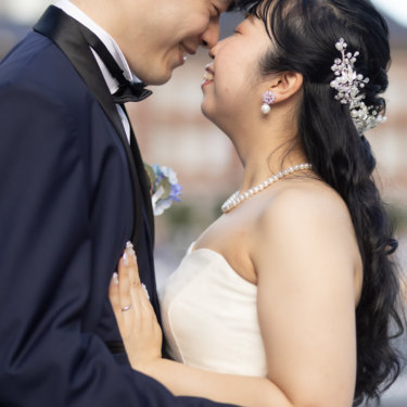 頬を寄せ合って微笑む新郎新婦のクローズアップ。パールのアクセサリーが輝くウェディングフォト