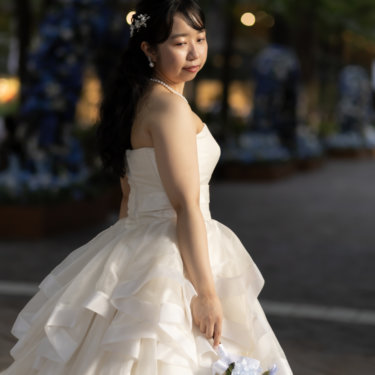 青い花のディスプレイを背に振り返る花嫁。ブルーのブーケとティアードドレスが映える丸の内の前撮り