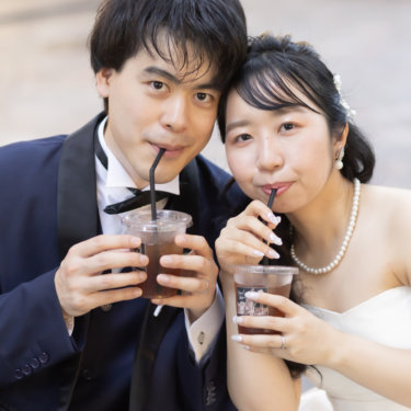 ストローでドリンクを飲みながらカメラを見る新郎新婦のクローズアップ。遊び心のあるフォトウェディング