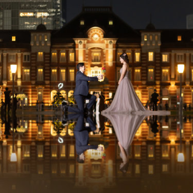 水鏡のリフレクション撮影。東京駅丸の内駅舎の前で片膝をつき、赤いバラを差し出す新郎とカラードレスの新婦
