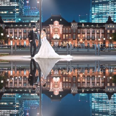 街灯と東京駅丸の内駅舎が水面に映り込むリフレクション撮影。夜景をバックに寄り添う新郎新婦の縦構図