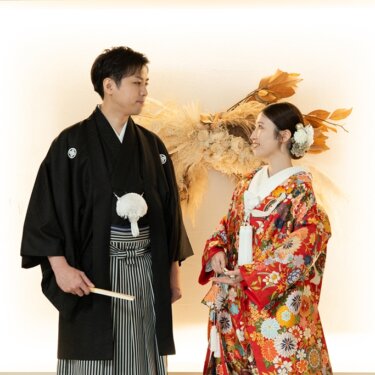 光る壁とドライフラワーの前で見つめ合う紋付袴の新郎と赤い色打掛の花嫁。南青山のスタジオで撮る和装前撮り。