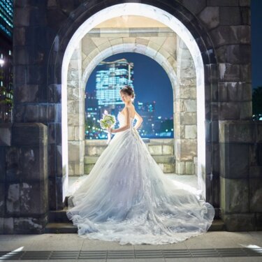 和田倉門の石造りアーチに縁取られ、丸の内の夜景を背に佇むウェディングドレスの花嫁のナイト前撮り