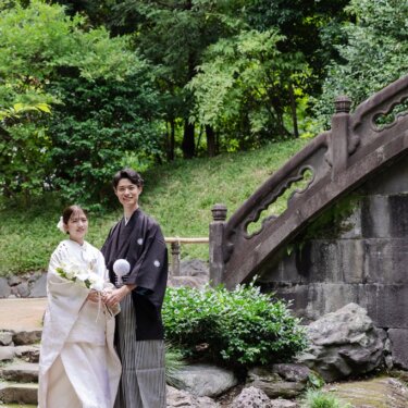 小石川後楽園の円月橋のそばに並んで立つ、黒紋付袴の新郎と白無垢の花嫁の和装前撮り