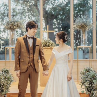 チャペルの祭壇前で見つめ合う新郎新婦。緑豊かな窓を背景にしたナチュラルウェディングフォト
