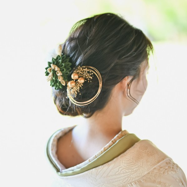 緑の葉と金色の実をあしらった和のヘアアクセサリー、後ろ姿のクローズアップ。
