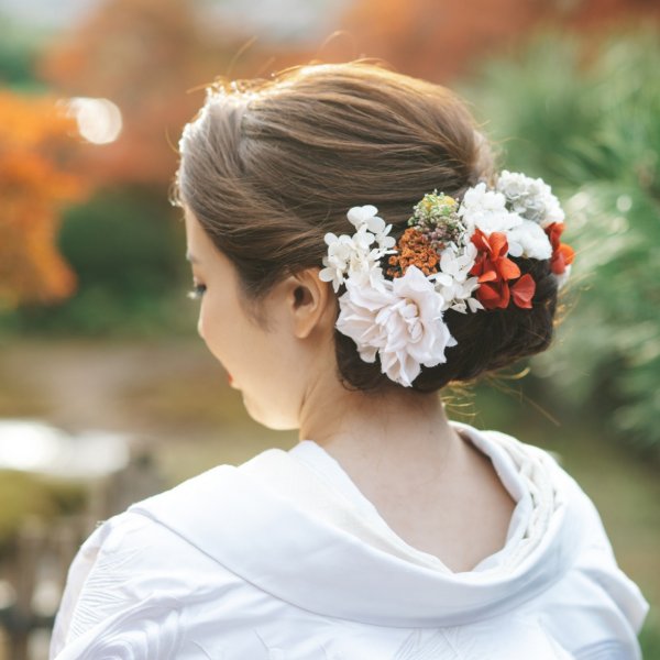 白い生花と赤いあしらいの髪飾り、色打掛の後ろ姿ヘアスタイル。