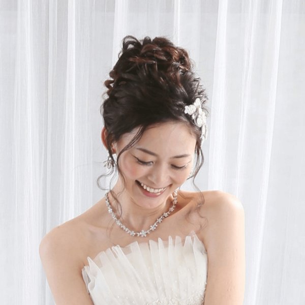 白いパールのビジューヘアアクセサリーとネックレスを合わせた、シンプルなドレス姿の花嫁の上品なアップスタイル。