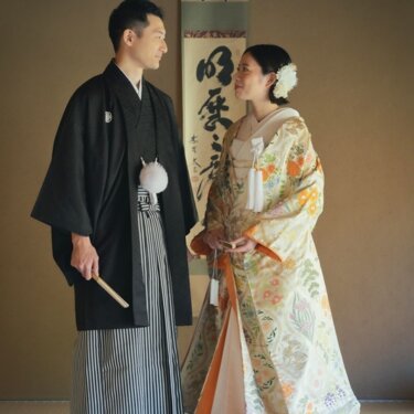 目白庭園の掛け軸が飾られた和室で見つめ合う、黒紋付袴の新郎とベージュ花柄の色打掛の新婦の結婚写真