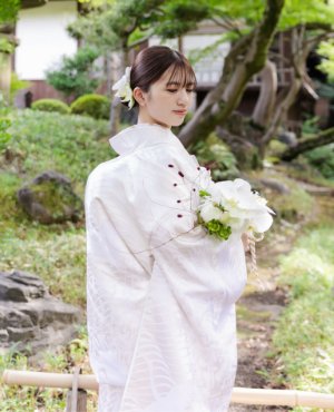 柔らかな曲線が流れるように描かれた白無垢。繊細な文様が光を受けて静かに輝き、花嫁の気品としなやかさを引き立てる一着です。