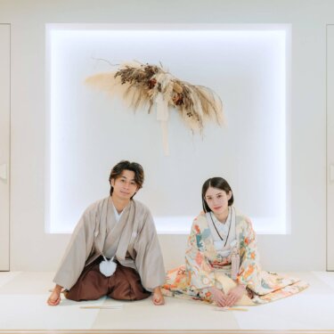 間接照明の白い壁の前に並んで座る紋付袴の新郎と色打掛の花嫁。南青山のスタジオで撮る和装前撮り