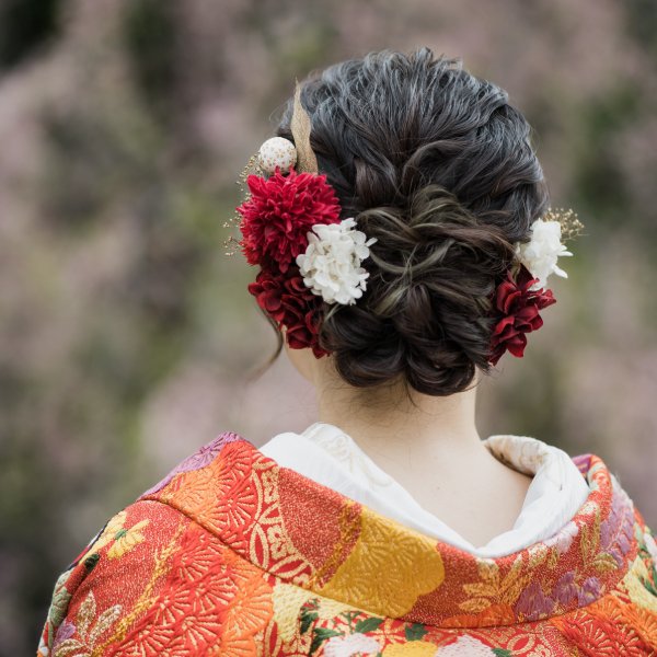 赤と白の生花を大胆にあしらった後ろ姿ヘアスタイル、朱色の色打掛。