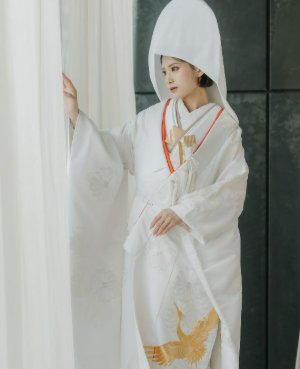 純白の白無垢に、白とゴールドの糸でほどこされた繊細な刺繍が上質な輝きを放ちます。さらに、他にはない赤いラインを配し伝統の中に凛とした個性を添えた、格調高い一着です。花嫁の清らかさと格式を美しく引き立て、特別な一日を永遠の記憶へと昇華させます。白無垢の中でも写真映えも格別です。和の美を体現する一着。