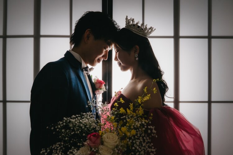 障子の逆光の中で額を寄せ合うネイビーのスーツの新郎とティアラのピンクのカラードレスの花嫁。東京駅店のスタジオで撮る洋装前撮り