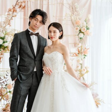 フラワーアーチの前に並ぶチェック柄タキシードの新郎とウェディングドレスの花嫁。南青山のラウンジスタジオでの洋装前撮り