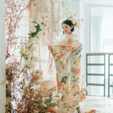 白いバラとドライフラワーのフラワーアーチの前で色打掛の袖を広げる花嫁。スタジオで撮る和装前撮りのポーズ